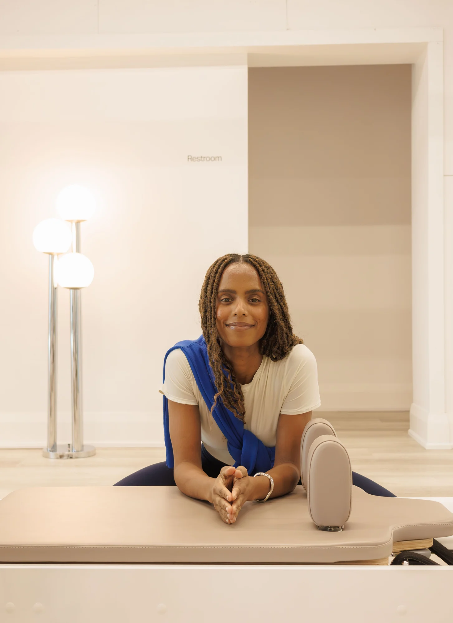 Portrait of a person seated at a treatment table, wearing a blue sweater over a white shirt