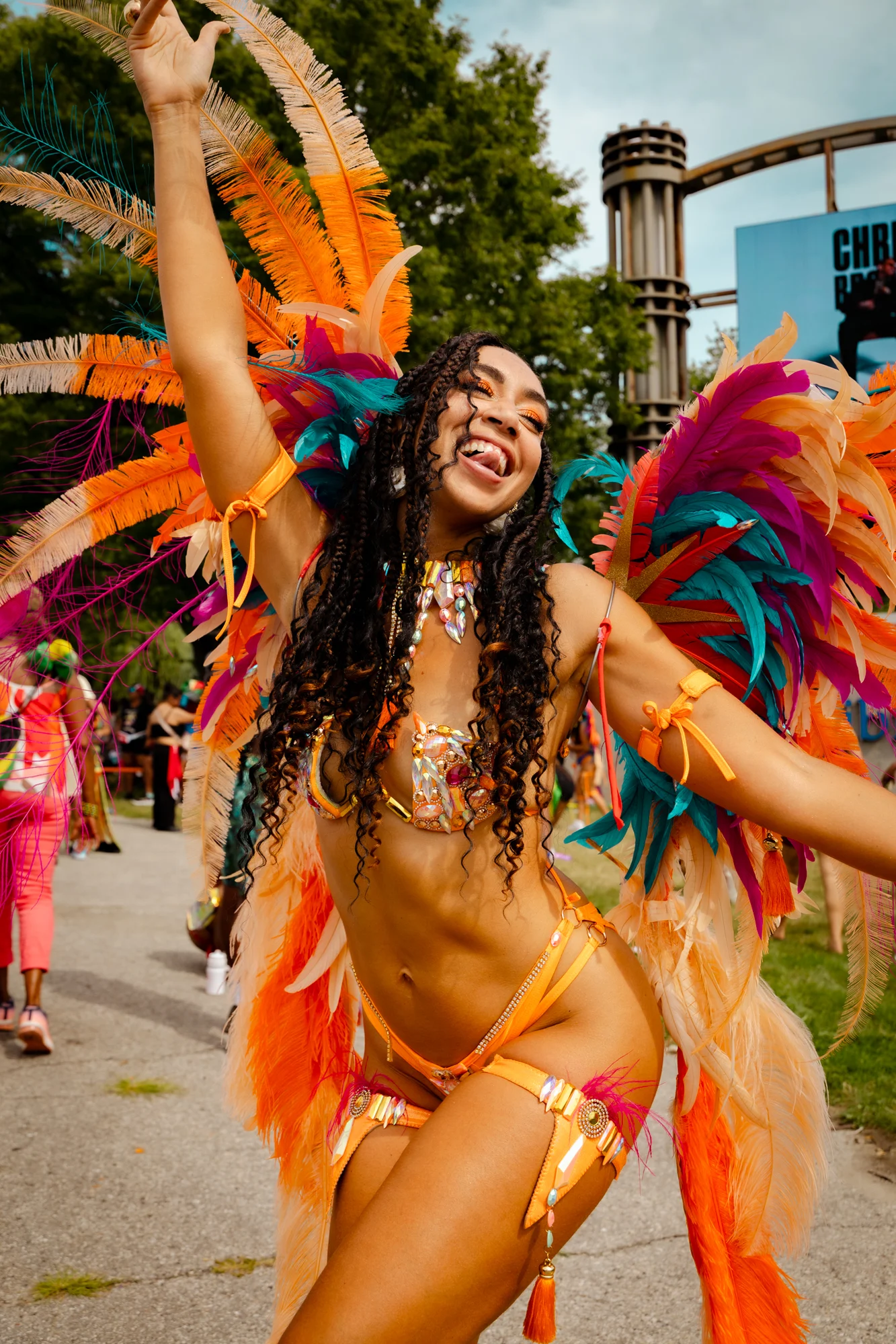 Carnival performer smiling in an orange feathered costume