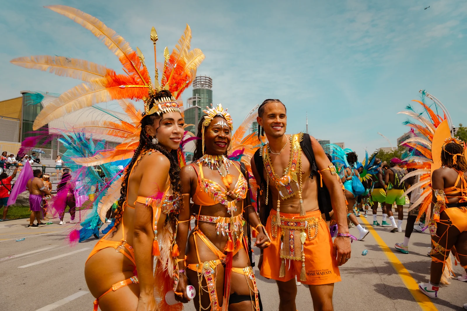 Three performers in orange costumes at Toronto Carnival