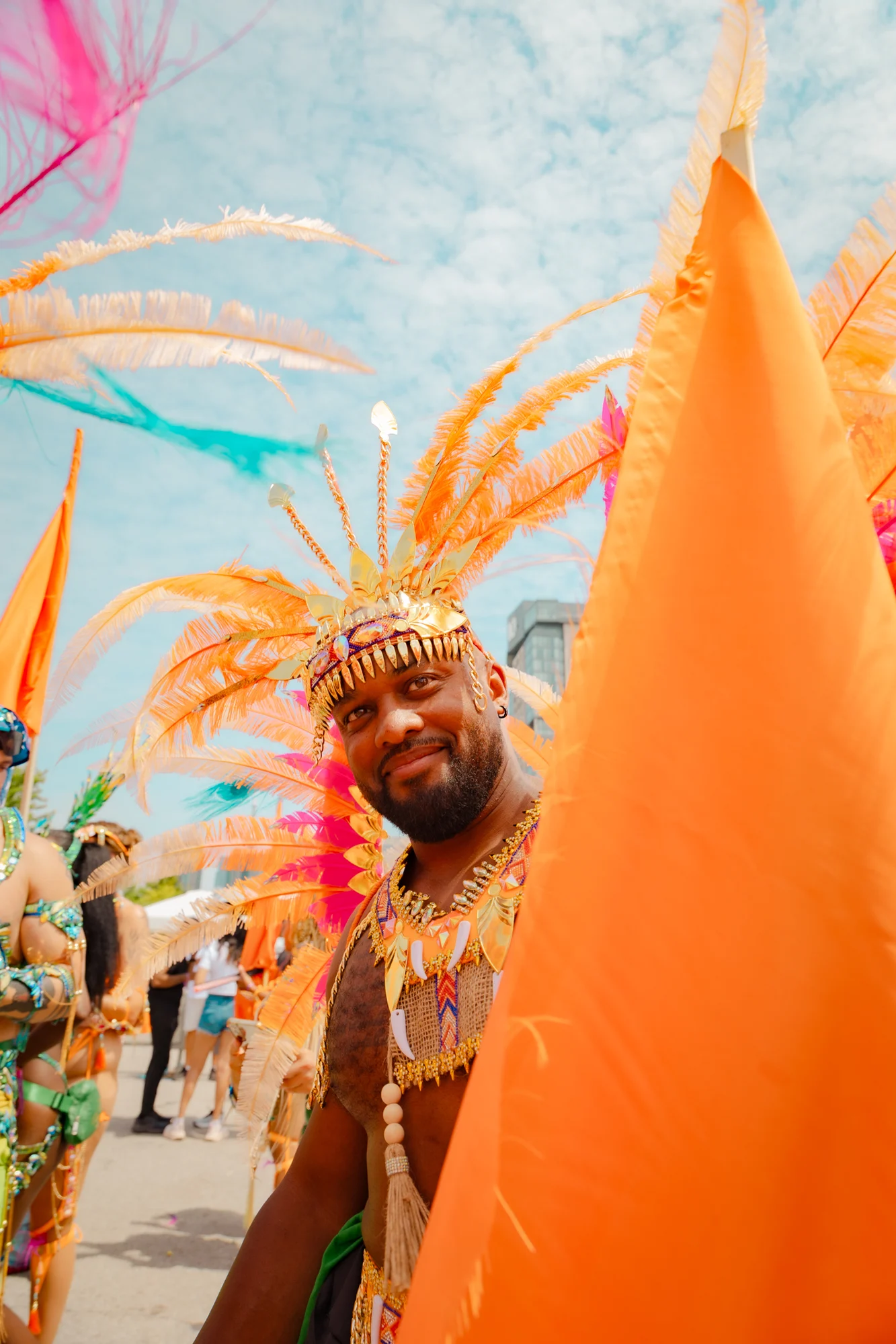 Portrait of a performer framed by orange costume feathers