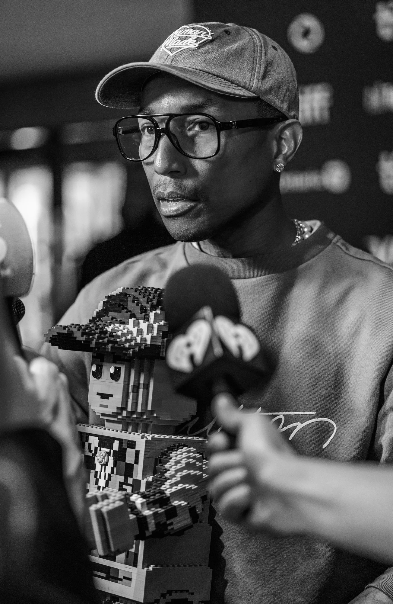 Black and white portrait of Pharrell Williams at a press event